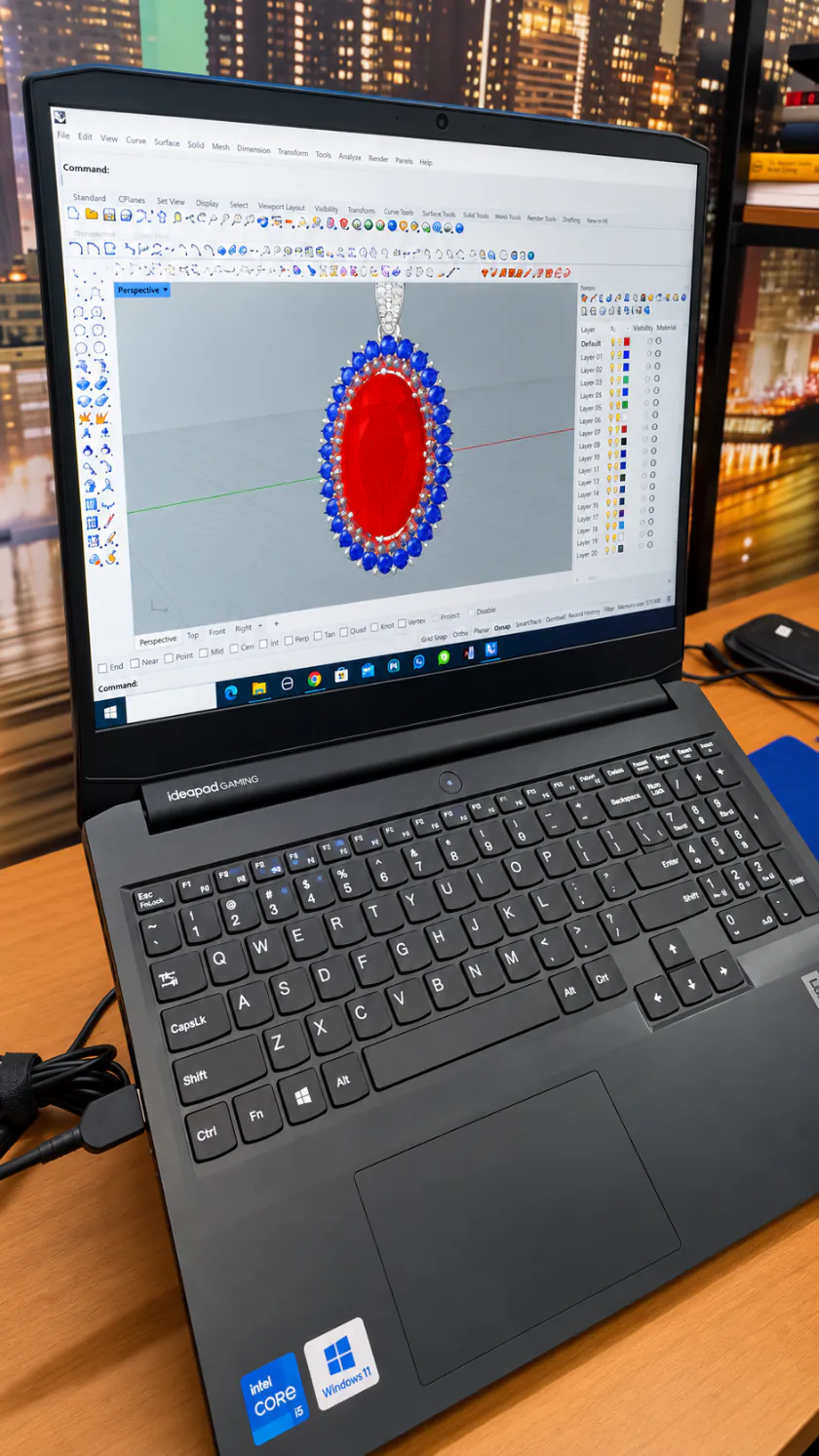 Tela do notebook com o modelo 3D de um pendente de pedra vermelha cercada de pedras azuis